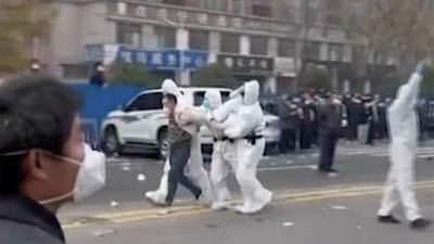 Security personnel in protective clothing were seen taking away a person during protest at the factory compound operated by Foxconn Technology Group who runs the world's biggest Apple iPhone factory in Zhengzhou in central China's Henan province. (AP) Security personnel in protective clothing were seen taking away a person during protest at the factory compound operated by Foxconn Technology Group who runs the world's biggest Apple iPhone factory in Zhengzhou in central China's Henan province. (AP)