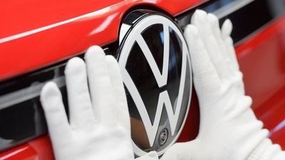 A technician attaches a Volkswagen logo to a car. (REUTERS)