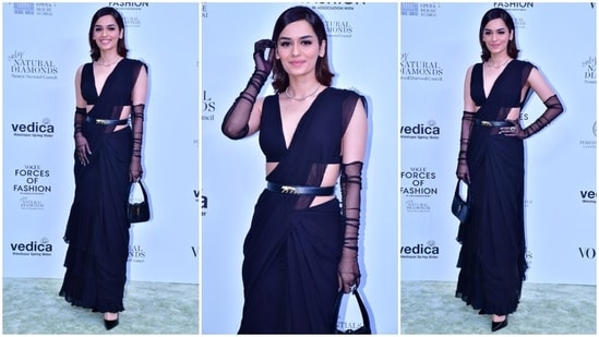 Manushi Chhillar attended Vogue India's Forces Of Fashion event in a sleeveless plunging neck blouse, a black chiffon saree and sheer Opera gloves.  She completed the outfit with a pearl necklace, a Sabyasachi belt, a YSL top handle bag, a statement ring, high heels, soft glam makeup and a short mane.(HT Photo/Varinder Chawla)