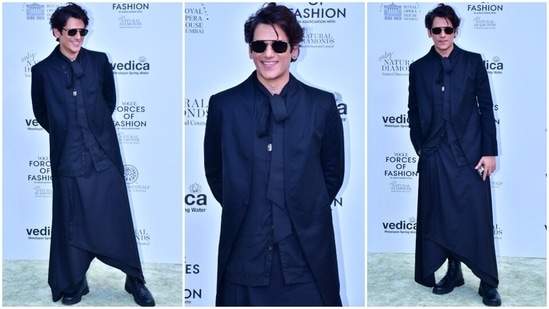 Vijay Varma made a stylish appearance at the event in an all-black outfit featuring a blazer with a train on the back, a button-down shirt and dhoti-style wrapover bottoms. He wore them with chunky lace-up combat boots, tinted sunglasses, and a messy hairdo.(HT Photo/Varinder Chawla)