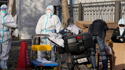 Covid In Beijing: Workers in protective clothing control access into a community under lockdown in Beijing. (AP) Covid In Beijing: Workers in protective clothing control access into a community under lockdown in Beijing. (AP)