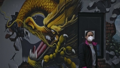 A woman wearing a face mask stands near a mural depicting a dragon in Beijing, Wednesday, amid the latest outbreak of Covid-19. (AP) A woman wearing a face mask stands near a mural depicting a dragon in Beijing, Wednesday, amid the latest outbreak of Covid-19. (AP)