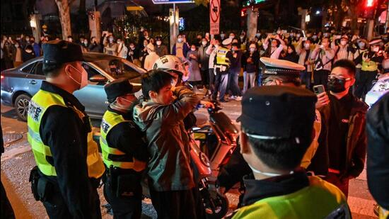 Police officers confront a man as they block Wulumuqi street, named for Urumqi in Mandarin, in Shanghai on Sunday, in the area where protests against China's zero-Covid policy took place the night before following a deadly fire in Urumqi, the capital of the Xinjiang region. (AFP)