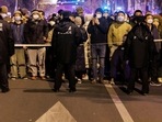 People stand behind a police cordon as they watch a protest over Covid restrictions, following a commemoration of the victims of a fire in Urumqi. 