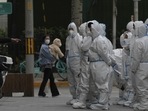 Workers in protective gear gather for their duties in Beijing.