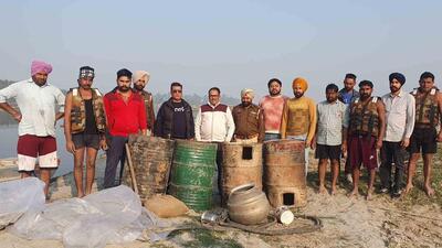 The excise department officials with 1.05 lakh litres of lahan recovered from the banks of Sutlej river in Ludhiana. (HT PHOTO)
