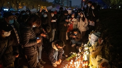 Demonstrators light candles for the victims of a deadly fire in the city of Urumqi during a protest in Beijing, China, on November 27. (Bloomberg) Demonstrators light candles for the victims of a deadly fire in the city of Urumqi during a protest in Beijing, China, on November 27. (Bloomberg)