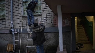 Two residents use food-packaging material to cover windows of a damaged building during a recent Russian strike while another resident lies inebriated at the entrance of a building in the southern city of Kherson, Ukraine, Sunday, Nov. 27, 2022. (AP Photo/Bernat Armangue) Two residents use food-packaging material to cover windows of a damaged building during a recent Russian strike while another resident lies inebriated at the entrance of a building in the southern city of Kherson, Ukraine, Sunday, Nov. 27, 2022. (AP Photo/Bernat Armangue)