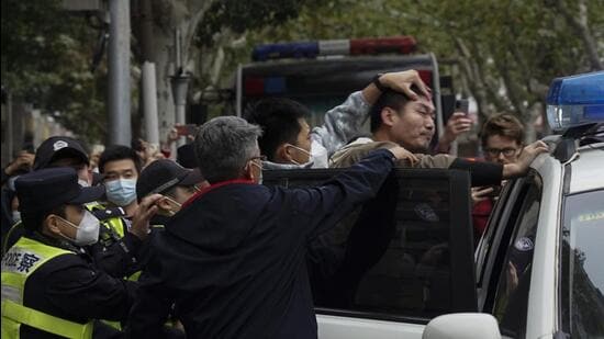 A demonstrator is forced into a police car by the police, during a protest on a street in Shanghai, China, on Sunday. (AP)
