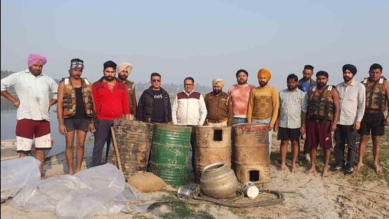 The excise department officials with 1.05 lakh litres of lahan recovered from the banks of Sutlej river in Ludhiana. (HT PHOTO)