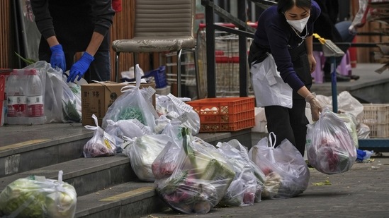 Workers wearing face masks prepare their customer's online order groceries outside a supermarket in Beijing, on November 28. Xi's unelected government doesn't seem too concerned with the hardships brought by the policy. This spring, millions of Shanghai residents were placed under a strict lockdown that resulted in food shortages, restricted access to medical care and economic pain.(Andy Wong / AP)