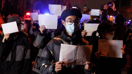 People hold white sheets of paper in protest over the Covid-19 restrictions, in Beijing, on November 27. The protests across China erupted aftera fire on November 24 that killed at least 10 people in an apartment building in the city of Urumqi, where some residents were locked in their homes for four months. That prompted an outpouring of angry questions online about whether firefighters or people trying to escape were blocked by locked doors or other pandemic restrictions.(Thomas Peter / REUTERS)
