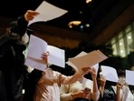Women hand out sheets of paper in protest over coronavirus disease (Covid-19) restrictions in mainland China, during a commemoration of the victims of a fire in Urumqi, at the University of Hong Kong (HKU), in Hong Kong, China November 29, 2022. (REUTERS/Tyrone Siu)