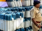 Police stand guard as polling officials check EVMs (Electronic Voting Machine) and other materials before dispatching them to the respective destinations ahead of India's Gujarat state's assembly elections, in Ahmedabad on November 10, 2022. (Photo by SAM PANTHAKY / AFP)