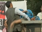 A woman hits a man with slippers on the stage of 'Beti Bachao' mahapanchayat by Hindu Ekta Manch in Delhi's Chattarpur area. (ANI) A woman hits a man with slippers on the stage of 'Beti Bachao' mahapanchayat by Hindu Ekta Manch in Delhi's Chattarpur area. (ANI)