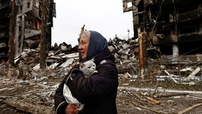 Russia-Ukraine War: A woman carries her cat as she walks past buildings that were destroyed by Russian shelling. (Reuters)
