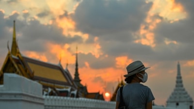 Thailand: A tourist wears a face mask to prevent spread of the coronavirus disease (Covid-19) during sunset near the Grand Palace in Bangkok, Thailand. (Representational)