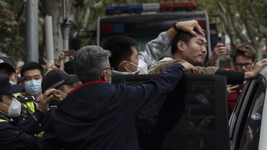 Covid Protests In China: A demonstrator is forced into a police car by the police, during a protest on a street in Shanghai, China.