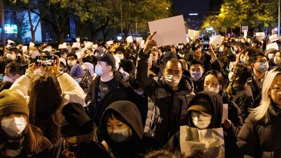 People hold white sheets of paper in protest of coronavirus disease (COVID-19) restrictions, after a vigil for the victims of a fire in Urumqi, as outbreaks of the coronavirus disease continue in Beijing, China. (REUTERS)
