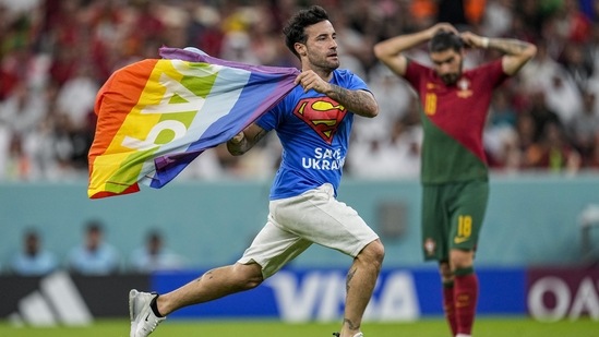 A pitch invader runs across the field with a rainbow flag during the World Cup group H soccer match between Portugal and Uruguay, at the Lusail Stadium in Lusail, Qatar, Monday, Nov. 28, 2022. (AP Photo/Abbie Parr)(AP)