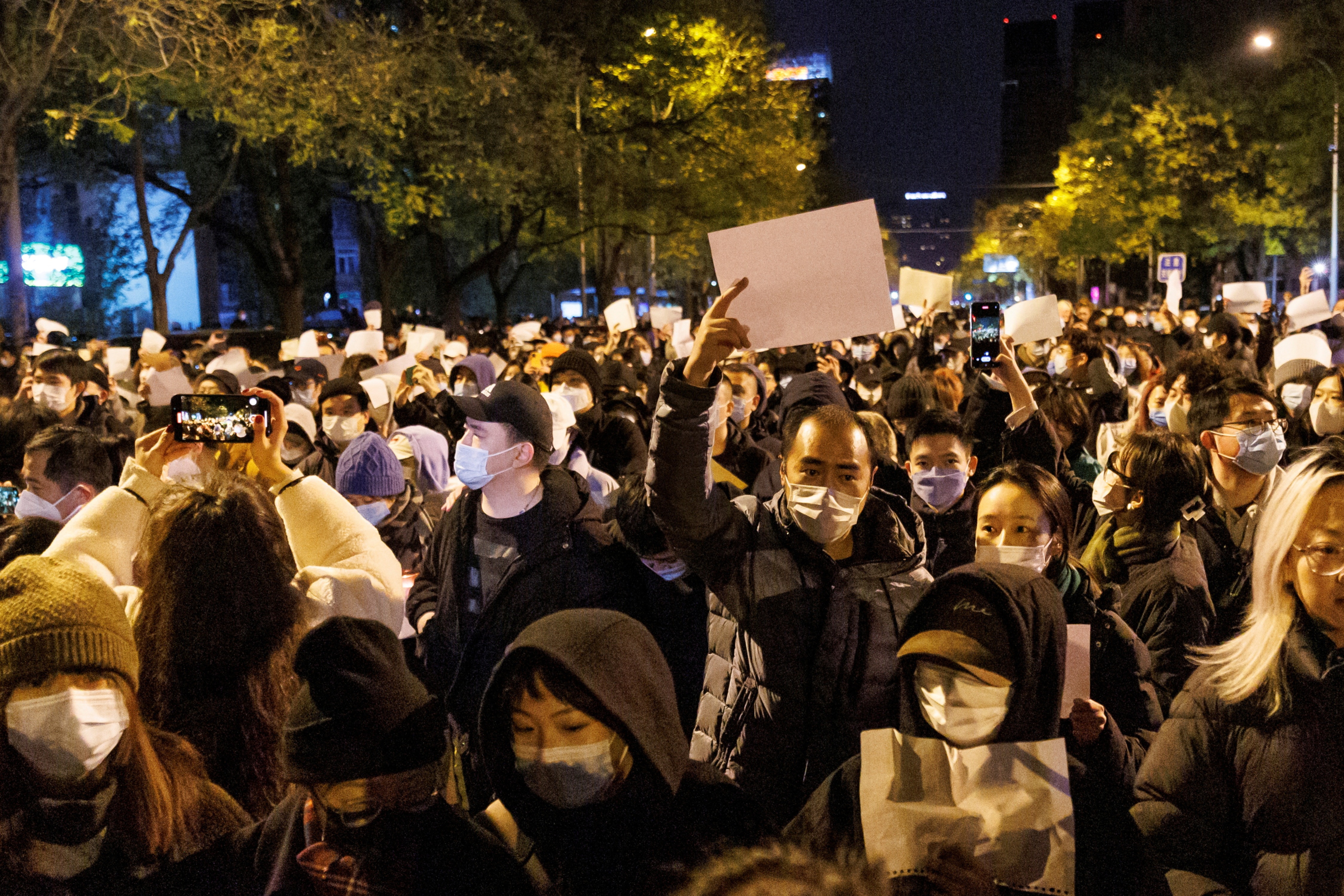 People hold white sheets of paper in protest of Covid-19 restrictions, after a vigil for the victims of a fire in Urumqi, as outbreaks of the coronavirus disease continue in Beijing, China. (Reuters)