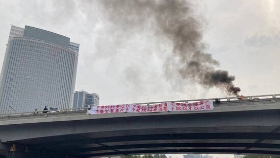 China Protests: Smoke rises as a banner with a protest message hangs off Sitong Bridge, Beijing, China.(Reuters)