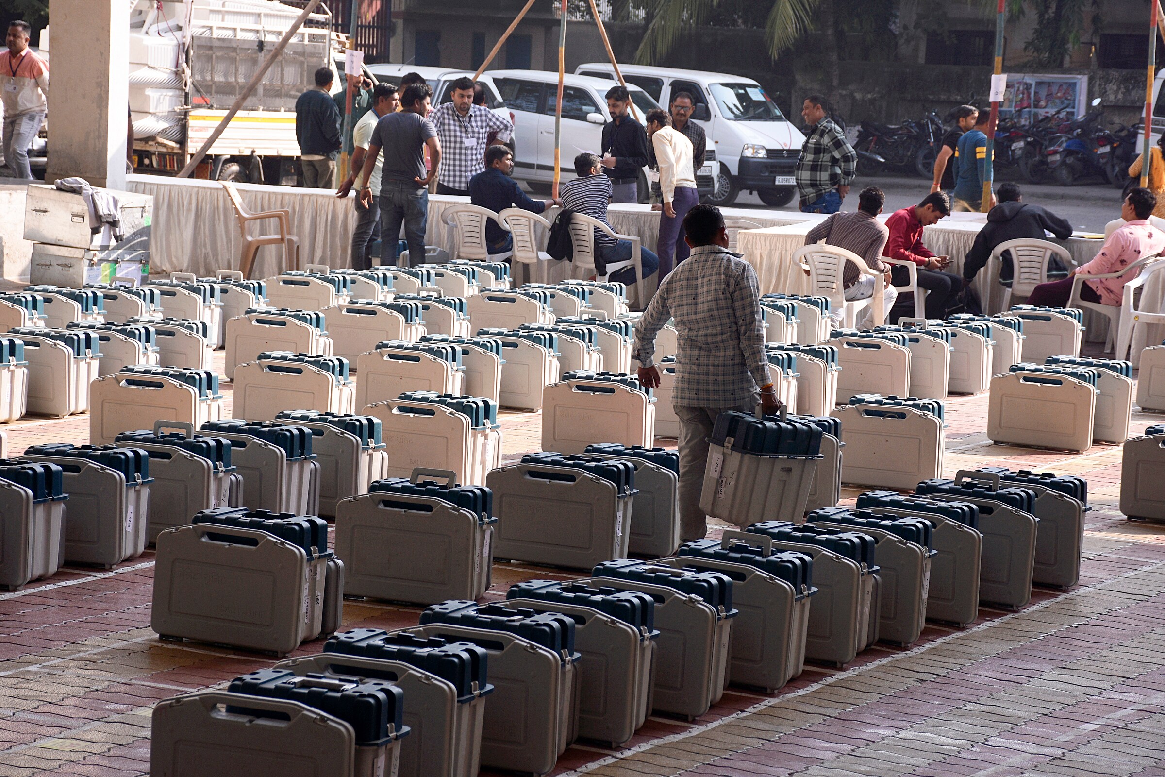 A polling official carries the Electronic Voting Machines (EVMs) prior to leaving for the polling station on the eve of the first phase of the Gujarat Assembly elections, in Surat on Wednesday. (ANI Photo) (Ashok Munjani)
