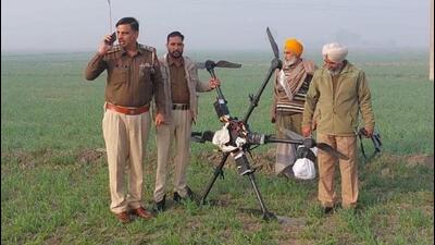 Punjab Police personnel with the drone carrying 5kg of heroin that was shot down by the Border Security Force at the India-Pakistan border in Khemkaran village of Tarn Taran district on Friday. (HT Photo)