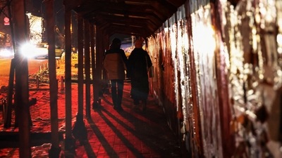 Russia-Ukraine War: People walk on a sidewalk illuminated by automobile headlights during power outages in Kyiv. (Reuters)
