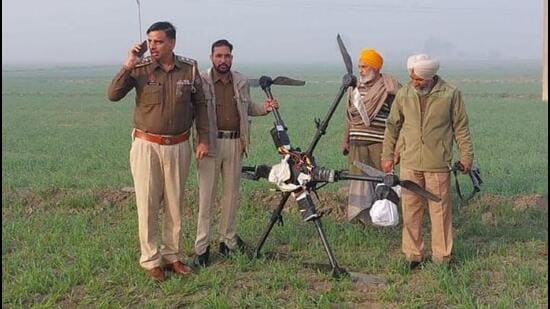 Punjab Police personnel with the drone carrying 5kg of heroin that was shot down by the Border Security Force at the India-Pakistan border in Khemkaran village of Tarn Taran district on Friday. (HT Photo)