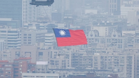 China-Taiwan Conflict: A Chinook helicopter carrying a Taiwan flag flies over the city during the country's National Day celebration in Taipei, Taiwan.(Reuters)