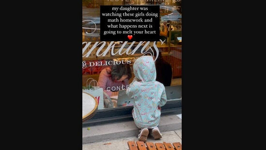 The image, taken from the viral video, shows the kid looking through a glass window watching two girls do their homework. (Instagram/@mary_sunshinelife)