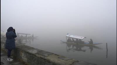 People ride shikaras in Dal Lake on a cold foggy morning in Srinagar on Sunday. (PTI)