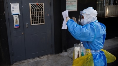 Covid In China: A health worker in protective suit checks the address of a resident to administer a Covid test. (Reuters)