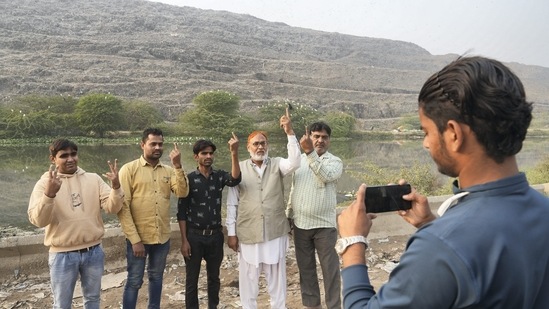People pose for a photograph near the Ghazipur landfill after casting their vote on Sunday. (PTI)