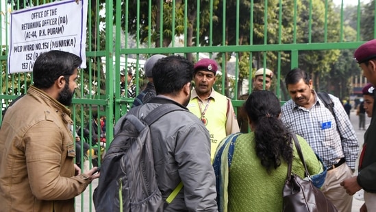 New Delhi, Dec 03 (ANI): Polling officials interact with police officials outside a polling booth on the eve of Municipal Corporation of Delhi (MCD) elections on Saturday. (ANI Photo/ Amit Sharma)