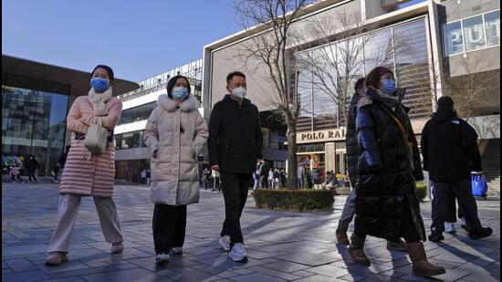 People wearing masks walk through a reopened open air shopping mall in Beijing, China, on Sunday. (AP)