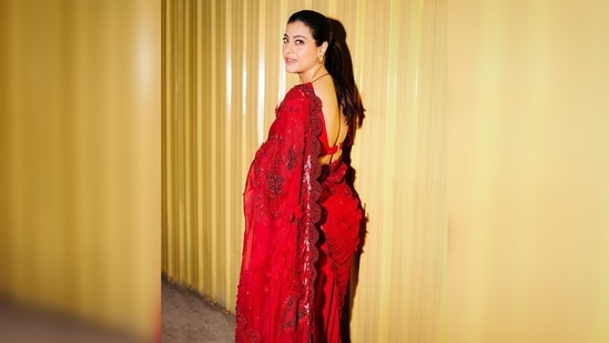 Kajol styled her saree with a plunging, backless neckline blouse featuring netted sleeves.(Instagram/@kajol)