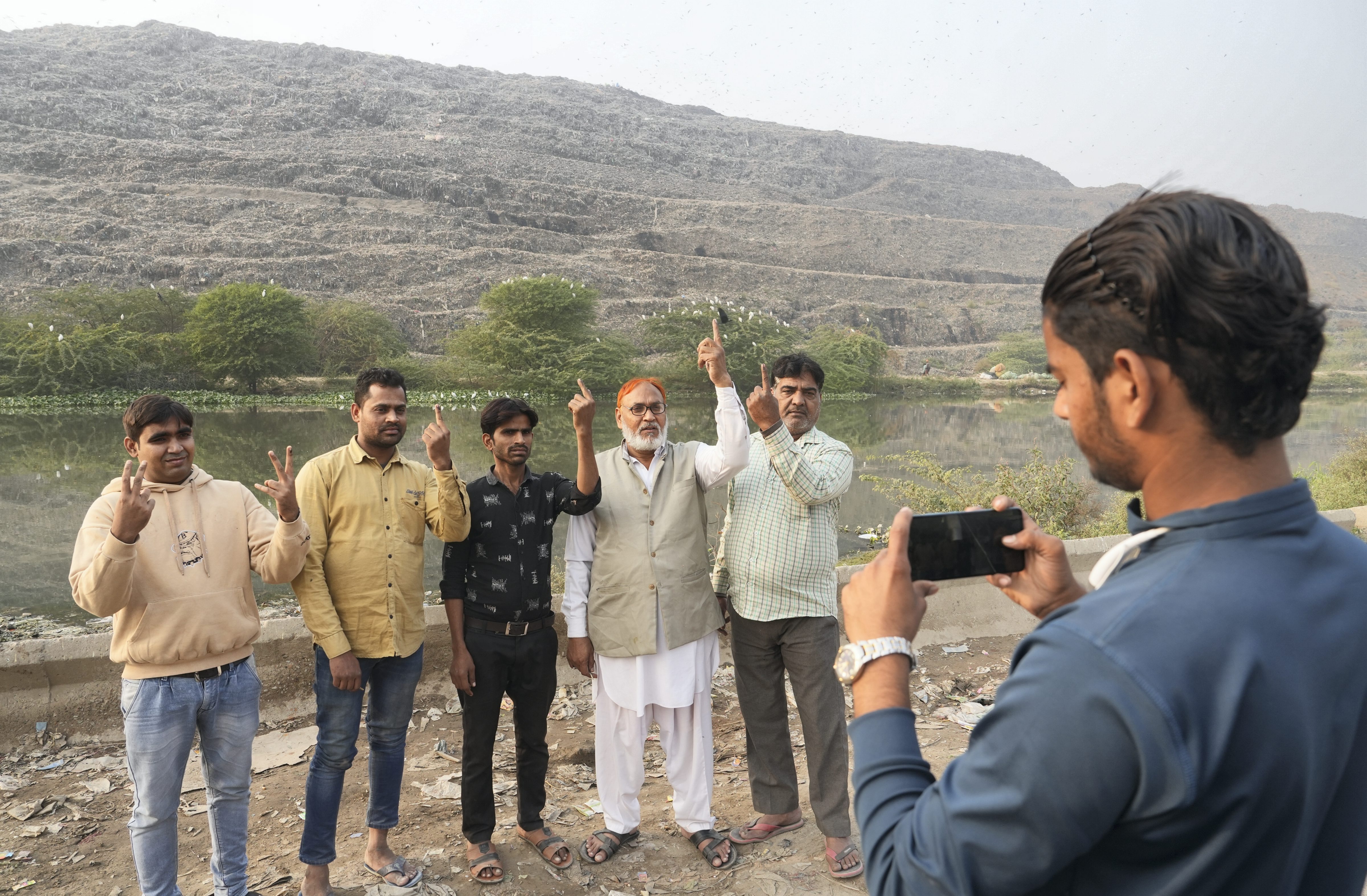People pose for a photograph near the Ghazipur landfill after casting their vote on Sunday. (PTI) People pose for a photograph near the Ghazipur landfill after casting their vote on Sunday. (PTI)
