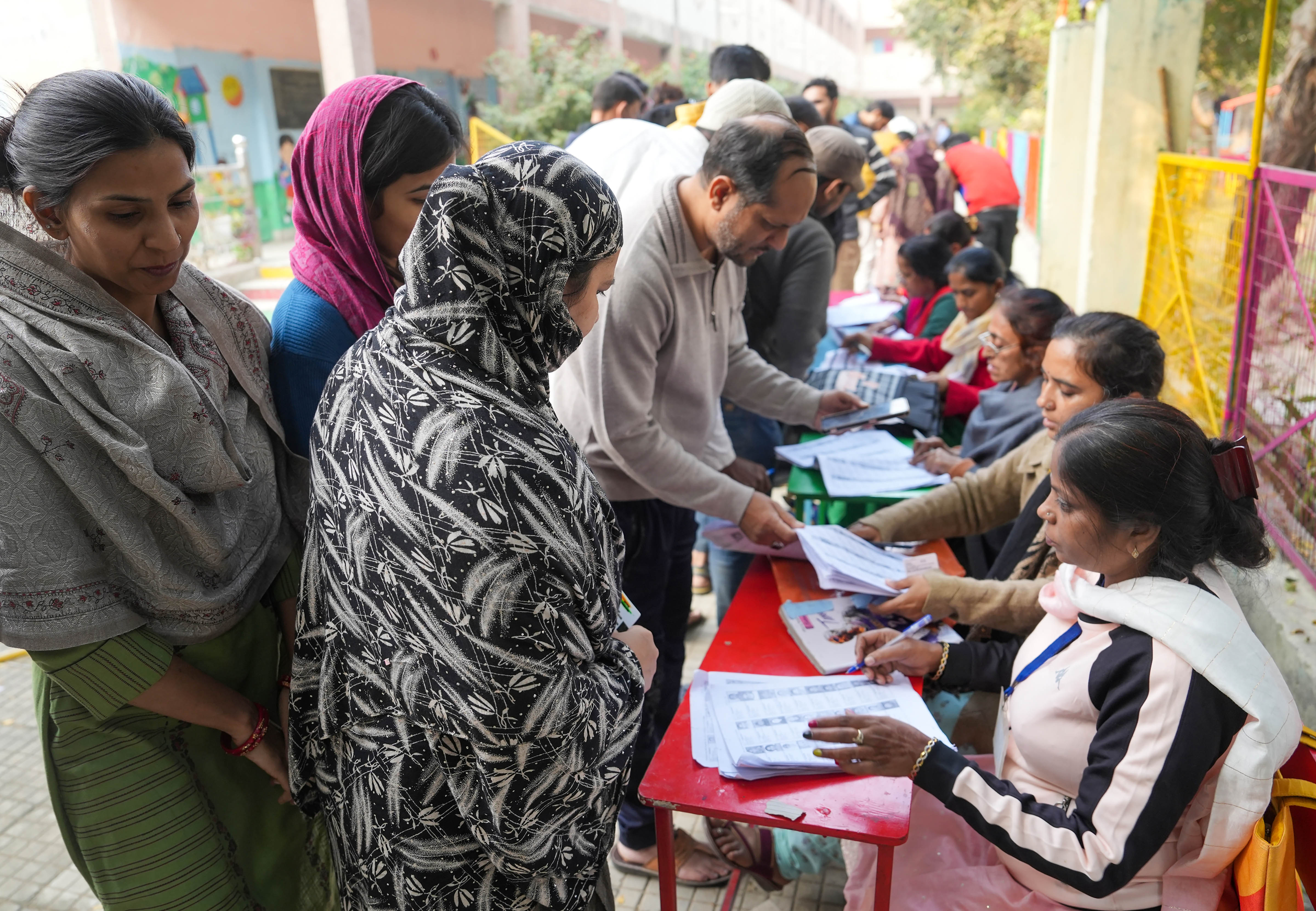 Polling agents look for the names of the people in a list as they come to cast their votes for the MCD elections, at a polling station in Khureji Khas, in East Delhi, Sunday, December 4, 2022. (PTI Photo/Manvender Vashist Lav) Polling agents look for the names of the people in a list as they come to cast their votes for the MCD elections, at a polling station in Khureji Khas, in East Delhi, Sunday, December 4, 2022. (PTI Photo/Manvender Vashist Lav)