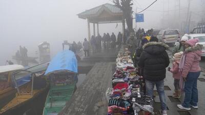 Tourists buying warm clothes at Boulevard Road along Dal Lake on a cold and foggy morning in Srinagar. The minimum temperature in the city plunged to minus 3.4 degrees Celsius on Sunday night. (PTI Photo)