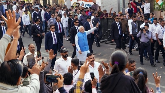 Prime Minister Narendra Modi waves to supporters on his way to the polling booth to cast his vote for the second phase of Gujarat assembly elections, in Ahmedabad on Monday. (ANI Photo)