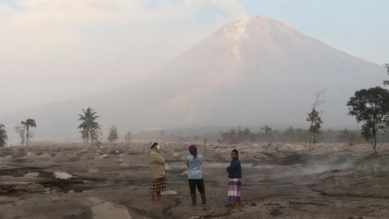 Villagers stand on an area covered in volcanic ash as Mount Semeru looms in the background in Kajar Kuning village in Lumajang, East Java, Indonesia, Monday, December 5, 2022. (AP Photo/Imanuel Yoga) Villagers stand on an area covered in volcanic ash as Mount Semeru looms in the background in Kajar Kuning village in Lumajang, East Java, Indonesia, Monday, December 5, 2022. (AP Photo/Imanuel Yoga)