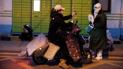 A woman presents her health code to a pandemic prevention worker to enter a residential compound in Beijing, on December 4. China's capital Beijing eased the Covid-19 restrictions across the country on December 6 following last month's historic protests. (Thomas Peter / REUTERS) A woman presents her health code to a pandemic prevention worker to enter a residential compound in Beijing, on December 4. China's capital Beijing eased the Covid-19 restrictions across the country on December 6 following last month's historic protests. (Thomas Peter / REUTERS)