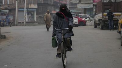 A man clad in woollens rides a bicycle on a cold and foggy morning in Srinagar on Tuesday. (AP)
