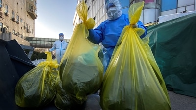 Workers in protective suits remove bags of medical waste outside a building where residents are isolating, in Beijing, on December 5. China's management of the disease may be downgraded as soon as January, to the less strict Category B from the current top-level Category A of infectious disease, Reuters reported. (Thomas Peter / REUTERS) Workers in protective suits remove bags of medical waste outside a building where residents are isolating, in Beijing, on December 5. China's management of the disease may be downgraded as soon as January, to the less strict Category B from the current top-level Category A of infectious disease, Reuters reported. (Thomas Peter / REUTERS)