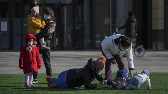 Residents with their children and toddlers play outside a mall in Beijing, on December 4. The shift brings China closer to what other countries have been saying for more than a year as they dropped restrictions and opted to live with the virus.(Andy Wong / AP)