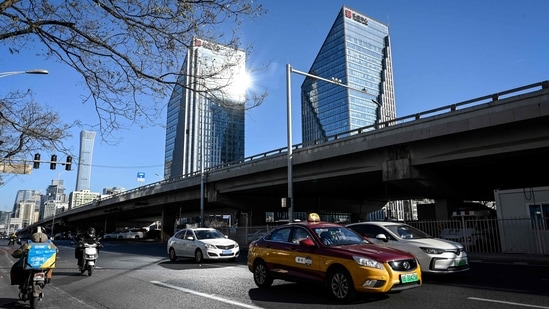Cars drive past as sirens are sounded in tribute to China's former leader Jiang Zemin, as his public memorial service takes place in Beijing on December 6. Despite reassurances from authorities, commuter traffic in major cities such as Beijing and Chongqing remains at a fraction of previous levels, Reuters reported.(Jade Gao / AFP)