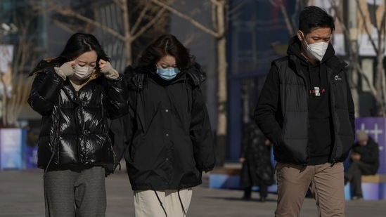 People walk through the Wangfujing shopping street after authorities started easing some of the anti-virus controls in Beijing, on December 6. Analysts now predict China may re-open the economy and drop border controls sooner than expected next year, with some seeing it fully open in spring.(Andy Wong / AP)