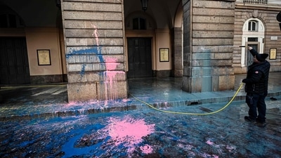An employee hoses the facade of the La Scala theater in Milan on December 7 after environmental activists from the "Last Generation" (Ultima Generazione) group smeared it with paint during a group's action aimed at raising awareness about climate change on the day of La Scala's new season's opening. (AFP)